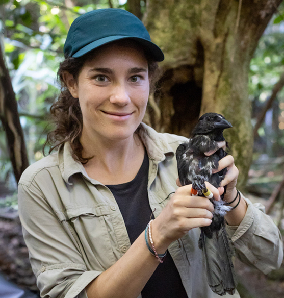Kaeli Swift, a white woman with brown, curly hair, holds up a live crow.